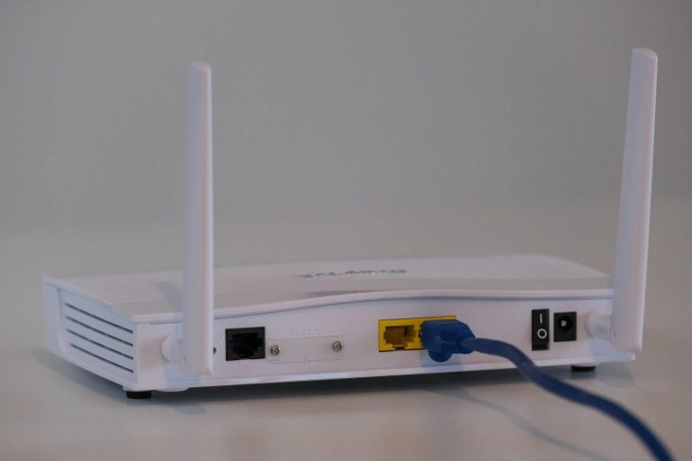 white voip router with blue cable on a white table